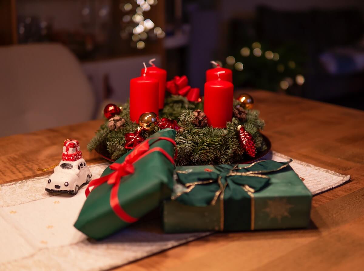 wrapped holiday presents on table next to wreath and candles
