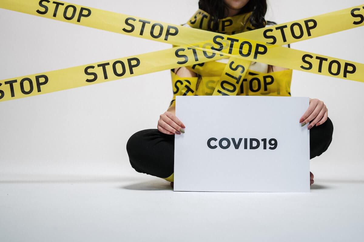 woman holding covid-19 sign with warning tape saying 