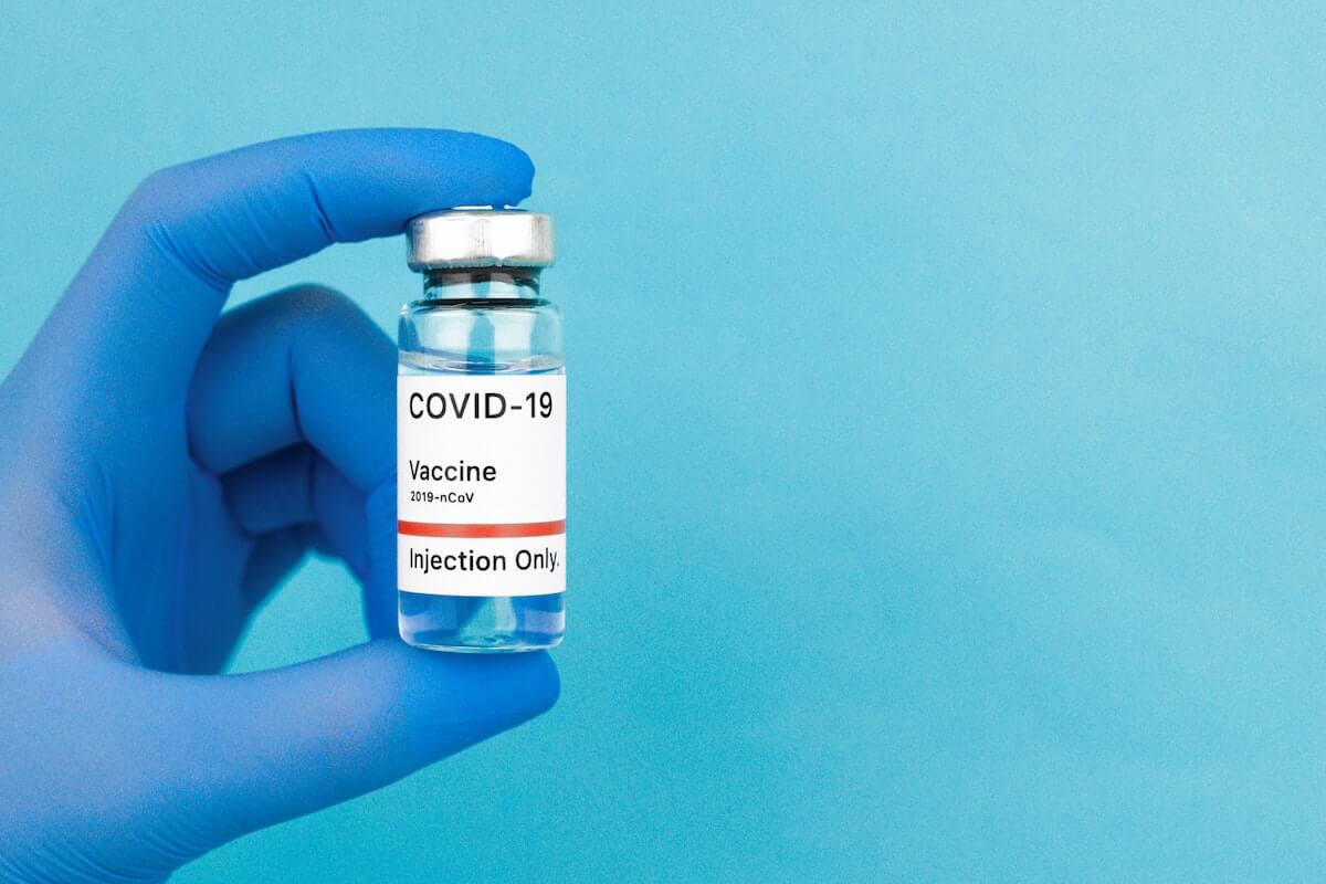 holding covid-19 vaccine bottle with medical glove
